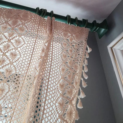 "Rideau élégant au design ajouré et décoratif, suspendu à une tringle verte dans un intérieur moderne. Idéal pour apporter une touche de charme et de lumière naturelle à votre salon ou chambre à coucher."
