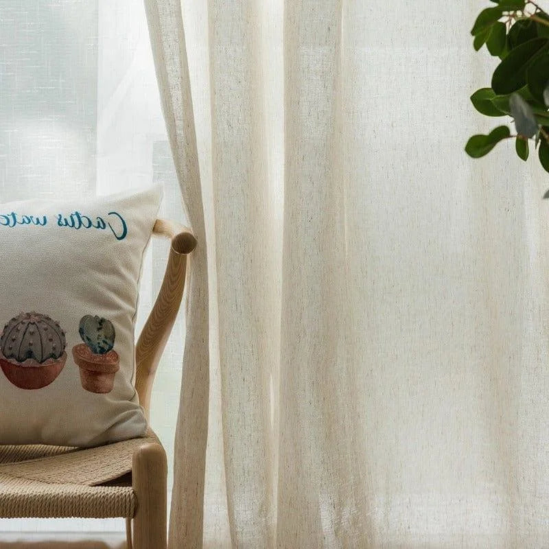 Coussin décoratif avec motifs de cactus sur chaise en bois clair, accompagné de rideaux clairs laissant passer une lumière douce, parfait pour une ambiance intérieure naturelle et apaisante. Ce design élégant s'intègre harmonieusement dans un salon ou une chambre, ajoutant une touche de nature et de style contemporain.