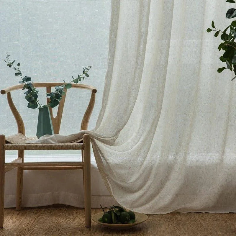 Rideau élégant blanc pour salon, drapé sur une chaise en bois. Mise en scène avec vase décoratif vert et feuillage, idéal pour créer une atmosphère apaisante. Parfait pour ajouter une touche de sophistication et de tranquillité à votre intérieur.