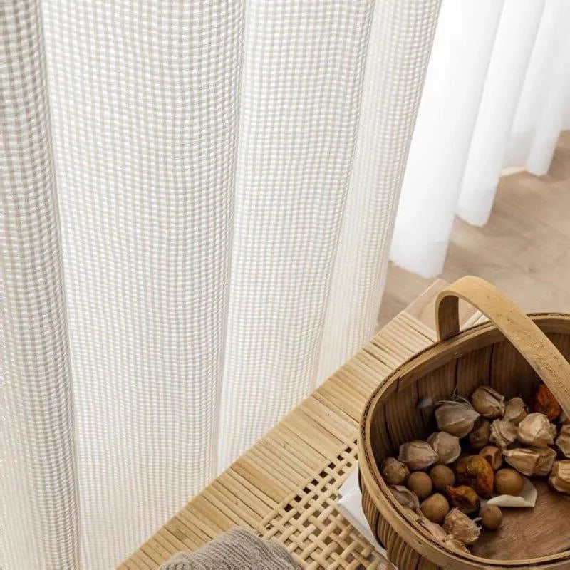 Rideaux à motifs géométriques élégants pour la décoration intérieure, présents dans un espace de vie éclairé par la lumière naturelle ambiante. À côté, un panier en osier contenant des éléments décoratifs naturels, idéal pour ajouter une touche rustique à votre maison. Solution parfaite pour embellir votre intérieur et créer une atmosphère cosy.