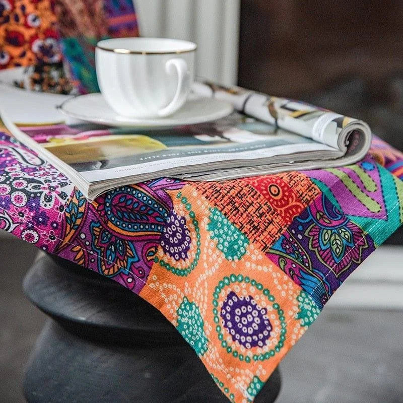 Nappe colorée bohème avec motifs géométriques et floraux, idéale pour ajouter une touche vibrante à votre table. Parfaite pour les repas entre amis ou les moments de détente, elle transforme instantanément votre espace en un lieu chaleureux et accueillant. Accessoirisée avec une tasse élégante et un magazine ouvert, elle invite à la convivialité et au style.