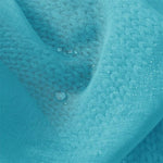 Gros plan sur un tissu bleu avec un motif texturé, montrant des gouttes d'eau reposant à sa surface, illustrant sa résistance à l'eau et son design élégant.