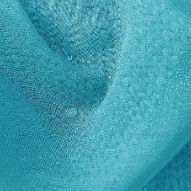 Gros plan sur un tissu bleu avec un motif texturé, montrant des gouttes d'eau reposant à sa surface, illustrant sa résistance à l'eau et son design élégant.