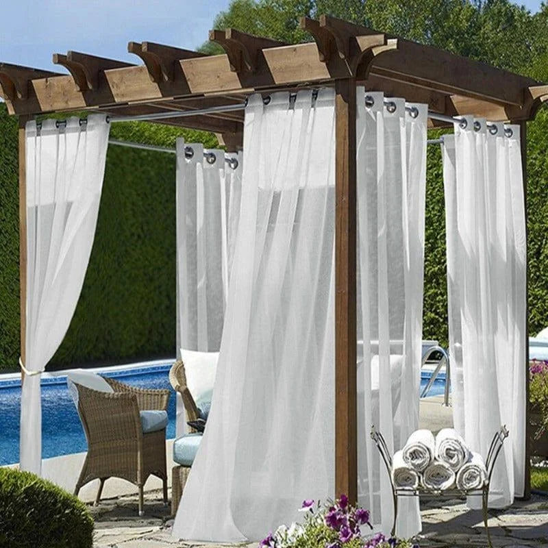 Pergola élégante avec voilages blancs et mobilier d'extérieur, idéale pour créer un espace détente près de la piscine. Profitez d'un cadre paisible alliant confort et style dans votre jardin ou sur votre terrasse. Cette installation offre à la fois intimité et ouverture sur la nature environnante, parfaite pour les moments de relaxation en plein air.