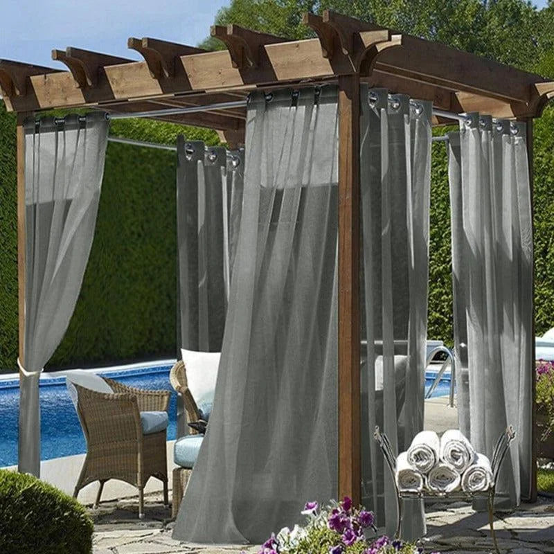 Pergola élégante pour terrasse avec rideaux gris, idéale pour créer un coin d'ombre raffiné près de la piscine. Ambiance extérieure paisible avec fauteuils confortables et vue sur jardin verdoyant. Accessoire parfait pour profiter d'instants de détente en plein air.