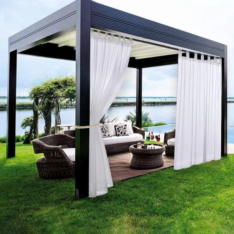Tonnelle de jardin moderne avec rideaux blancs et salon en osier, offrant un espace extérieur élégant avec vue sur un lac. Idéal pour les moments de détente en plein air, elle ajoute une touche de sophistication à votre jardin tout en offrant protection et intimité.