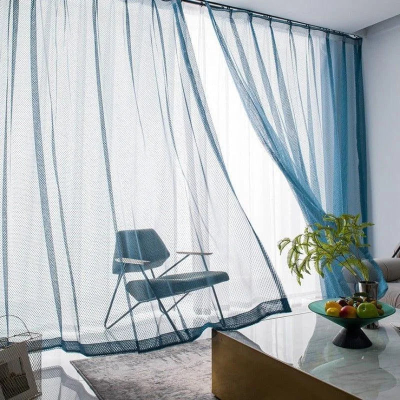 Rideaux élégants bleus dans un salon moderne avec fauteuil assorti. Lumière naturelle filtrée créant une ambiance apaisante. Décoration design avec table basse et plante verte. Parfait pour ajouter une touche contemporaine à votre intérieur.