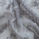 Texture délicate et élégante d'un tissu gris clair avec motifs subtils, idéal pour les créations de mode sophistiquées ou pour apporter une touche raffinée à votre décoration intérieure. Ce tissu offre un effet visuel captivant grâce à ses détails texturés uniques. Parfait pour les designers à la recherche d'un matériau distinctif et stylé.