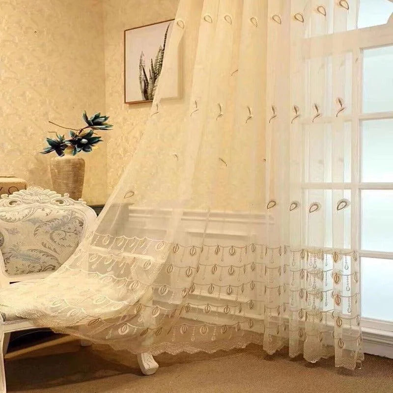 Voilage élégant dans un intérieur lumineux, mettant en valeur une ambiance chaleureuse et raffinée. Décoration murale en arrière-plan et fauteuil orné de motifs à volutes, créant une harmonie entre sophistication et douceur. Solution idéale pour habiller vos fenêtres avec grâce tout en préservant la lumière naturelle.