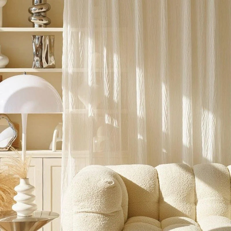 Salon moderne avec canapé confortable et lampe design, décoré avec des rideaux légers laissant passer la lumière naturelle. Espace de vie élégant et doux, avec des accessoires décoratifs sur une étagère. Idéal pour créer une ambiance chaleureuse et accueillante.