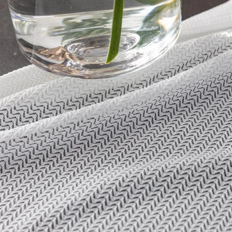 Tissu à motif zigzag noir et blanc sous un vase en verre, idéal pour ajouter une touche moderne et élégante à votre décoration intérieure. Parfait pour des projets de couture ou de design d'intérieur nécessitant une esthétique contemporaine.