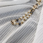 Collier élégant avec perles blanches et noires sur fond texturé. Accessoire raffiné pour compléter une tenue chic avec une touche glamour. Design intemporel parfait pour toutes les occasions. Charmante inclusion de détails dorés ajoutant une touche sophistiquée.
