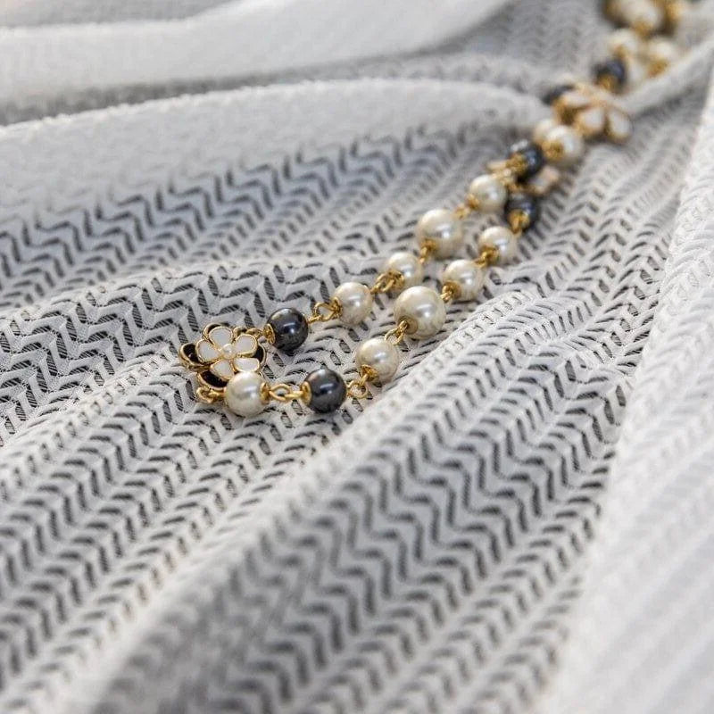 Collier élégant avec perles blanches et noires sur fond texturé. Accessoire raffiné pour compléter une tenue chic avec une touche glamour. Design intemporel parfait pour toutes les occasions. Charmante inclusion de détails dorés ajoutant une touche sophistiquée.