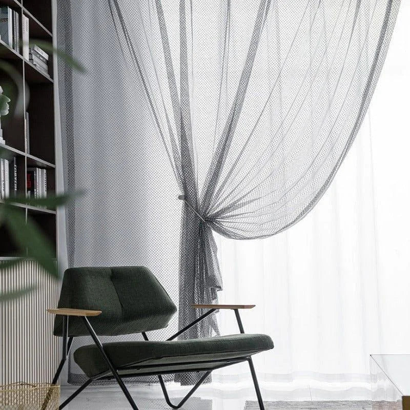 Fauteuil design moderne avec accoudoirs en bois, placé devant une grande fenêtre avec rideaux élégants, ajoutant une touche de sophistication à un intérieur contemporain. Décoration idéale pour un salon chaleureux et stylé.