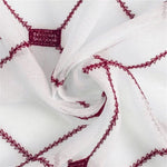 Image d'un tissu blanc orné de motifs brodés rouges, idéal pour la décoration intérieure, avec un design géométrique unique et élégant, parfait pour ajouter une touche de sophistication à toute pièce de la maison.