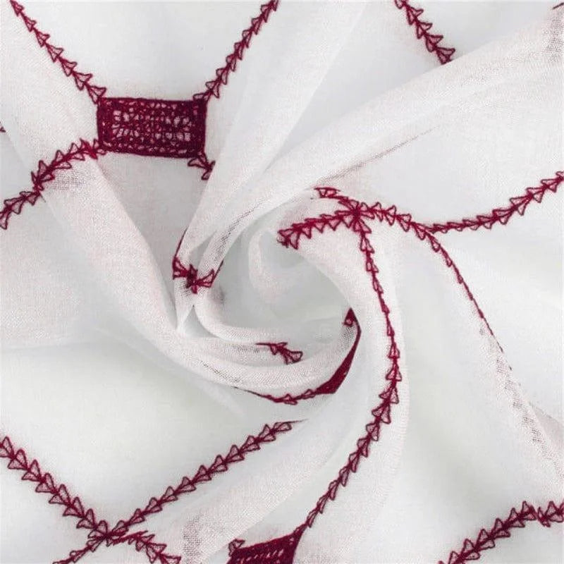 Image d'un tissu blanc orné de motifs brodés rouges, idéal pour la décoration intérieure, avec un design géométrique unique et élégant, parfait pour ajouter une touche de sophistication à toute pièce de la maison.