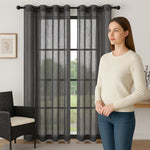Femme observant un voilage gris foncé à œillets installé dans un salon moderne, avec vue sur jardin.