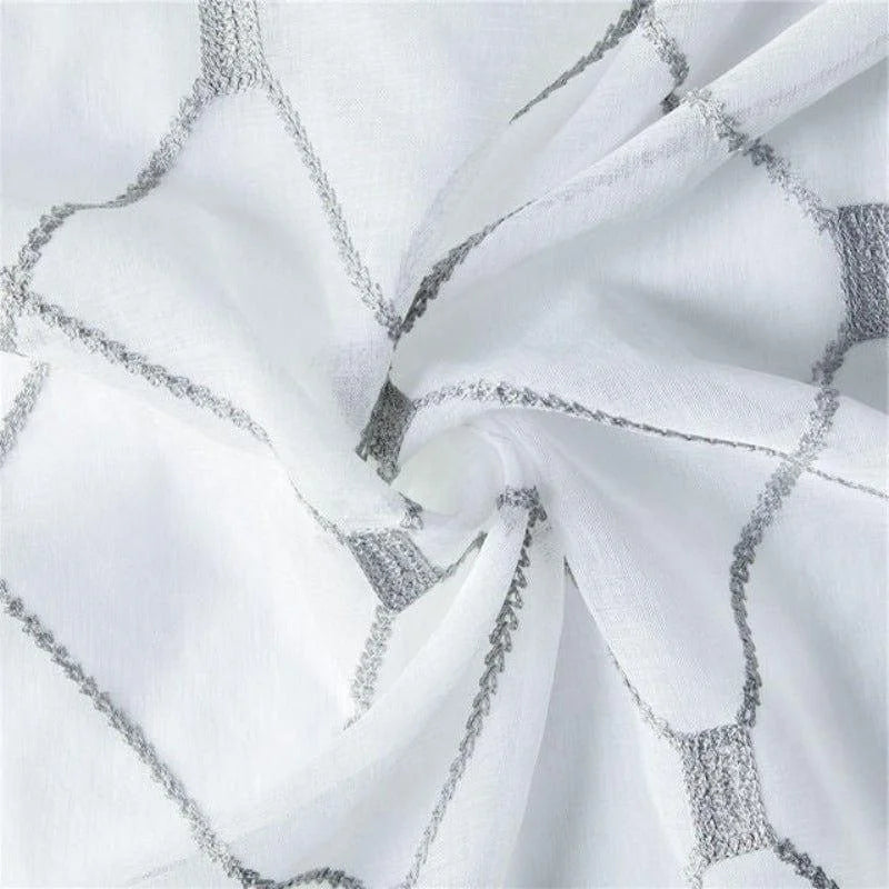 Image d'un tissu blanc aux motifs géométriques gris, idéal pour la confection de rideaux modernes. Design élégant et contemporain, parfait pour ajouter une touche de sophistication à votre décoration intérieure. Ce textile harmonieux s'intègre facilement dans divers styles d'aménagement.