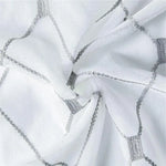 Image d'un tissu blanc aux motifs géométriques gris, idéal pour la confection de rideaux modernes. Design élégant et contemporain, parfait pour ajouter une touche de sophistication à votre décoration intérieure. Ce textile harmonieux s'intègre facilement dans divers styles d'aménagement.