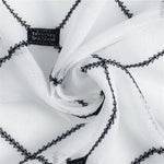Tissu décoratif blanc avec motifs géométriques noirs, idéal pour la confection de vêtements ou la décoration intérieure, offrant un style moderne et élégant.