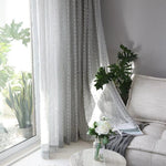 Voilage gris élégant pour salon moderne, filtre la lumière naturelle, s'accorde avec décoration intérieure minimaliste, crée une ambiance apaisante et raffinée, idéal pour fenêtres de grand format, ajout de plantes vertes autour, générant une atmosphère harmonieuse et confortable.