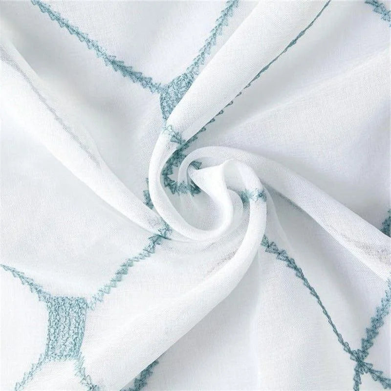Tissu décoratif blanc avec motifs géométriques bleus, parfait pour la confection de rideaux élégants ou de linge de maison moderne. Design lumineux et tendance pour une décoration d'intérieur rafraîchissante.