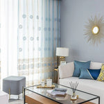 Rideaux élégants et contemporains pour salon moderne, offrant une touche de sophistication avec leurs motifs géométriques. Parfaits pour filtrer la lumière et ajouter du style à votre décor intérieur. Combine harmonieusement avec une décoration chic comprenant un canapé blanc, des coussins bleus et une table basse en verre. Accentue l'élégance de la pièce grâce à un design raffiné et intemporel.