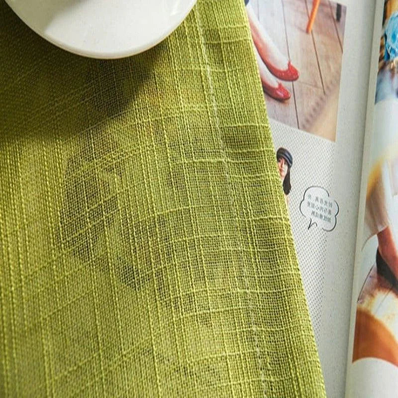 Produit textile vert posé sur une table avec un magazine ouvert en arrière-plan. Design moderne et élégant, idéal pour ajouter une touche de couleur à votre décoration intérieure. Accessoire parfait pour donner du style à votre maison.