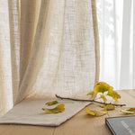 Rideau beige élégant pour décoration intérieure, idéal pour un salon lumineux, avec un motif texturé, accompagné de feuilles automnales sur une table en bois. Parfait pour ajouter une touche naturelle et chaleureuse à votre maison.