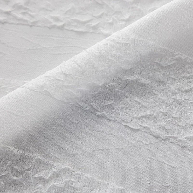Texture élégante et finement détaillée d'un tissu blanc aux motifs délicats, parfait pour la décoration intérieure moderne et raffinée. Convient idéalement pour la confection de rideaux ou de voilages apportant une touche de légèreté et de sophistication à tout espace de vie.
