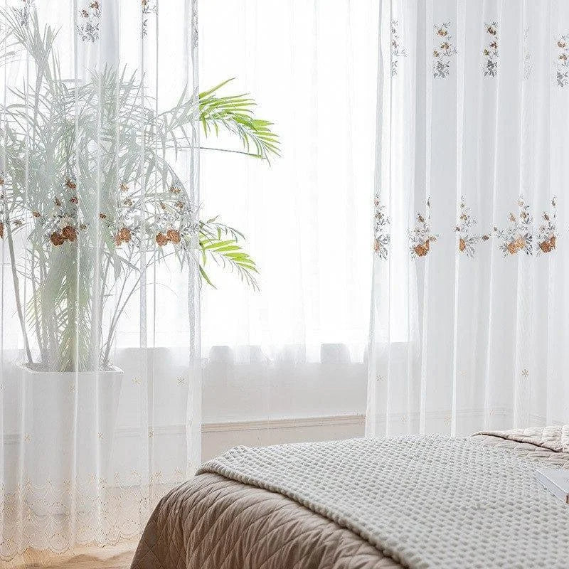 Voilage blanc avec motifs floraux, idéal pour ajouter une touche élégante et lumineuse à votre intérieur. Parfait pour une chambre ou un salon, il filtre doucement la lumière tout en préservant l'intimité. Plante d'intérieur en pot ajoutant une ambiance naturelle et relaxante à votre espace. Style moderne et épuré.