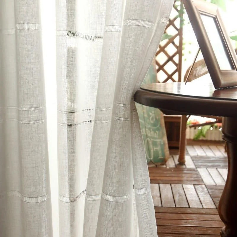 Voilage blanc élégant, idéal pour apporter une touche de luminosité à votre intérieur. Parfait pour une ambiance chaleureuse avec une vue sur un balcon en bois. Intégration harmonieuse dans un décor moderne ou classique. Accessoire déco idéal pour salon, chambre ou salle à manger.