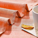 Nappe de table élégante de couleur orange, parfaite pour apporter une touche chaleureuse à votre décoration. Idéale pour les repas en intérieur ou extérieur, elle met en valeur vos tables avec style et simplicité. Accessoirisée ici avec une tasse et une tranche de fruit séché pour une ambiance conviviale.