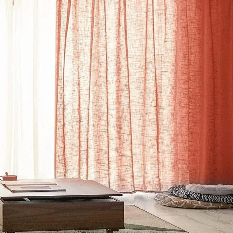 Rideaux rouges élégants filtrant la lumière du jour, idéals pour une ambiance chaleureuse dans le salon. Table basse moderne en bois, entourée de coussins confortables au design unique, parfaite pour une décoration intérieure contemporaine.