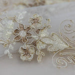 Dentelle brodée délicate avec motifs floraux en relief, idéale pour la confection de vêtements élégants et sophistiqués, parfaite pour ajouter une touche de raffinement à une tenue.