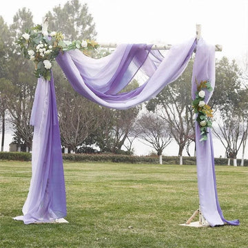 Arche de cérémonie élégante pour mariage, décorée de drapés violets et accents floraux blancs, idéale pour un événement en plein air. Cadre de fond naturel avec arbres et pelouse verdoyante, créant une atmosphère romantique et sereine. Parfaite pour des photos mémorables de mariage ou d'événements spéciaux.