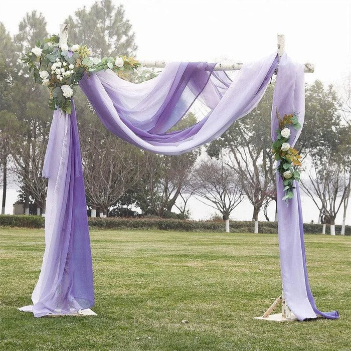 Arche de cérémonie élégante pour mariage, décorée de drapés violets et accents floraux blancs, idéale pour un événement en plein air. Cadre de fond naturel avec arbres et pelouse verdoyante, créant une atmosphère romantique et sereine. Parfaite pour des photos mémorables de mariage ou d'événements spéciaux.