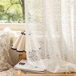 Voilage blanc élégant avec motifs décoratifs suspendu près d'une fenêtre, apportant une ambiance lumineuse et raffinée à votre intérieur. Idéal pour ajouter une touche de charme à votre salon ou chambre à coucher.
