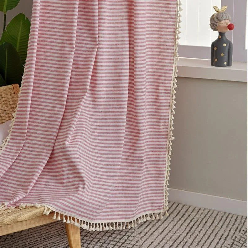 Couverture rayée rose avec franges beige, placée sur une chaise en bambou, ajoutant une touche cosy et élégante à la décoration intérieure. Parfaite pour rehausser le style d’un salon ou d’une chambre à coucher.