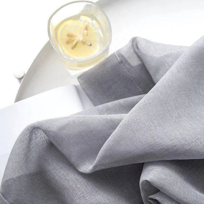 Serviette élégante gris clair disposée délicatement sur une table blanche, accompagnée d'un verre d'eau citronnée rafraîchissante. Idéale pour une décoration de table moderne et épurée, ajoutant une touche de sophistication à votre intérieur.