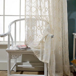 Voilage élégant beige avec motifs géométriques, suspendu près d'une fenêtre lumineuse. Idéal pour une décoration intérieure chic et apaisante. Ajoute une touche de sophistication à votre salon ou chambre, tout en laissant passer une douce lumière naturelle.