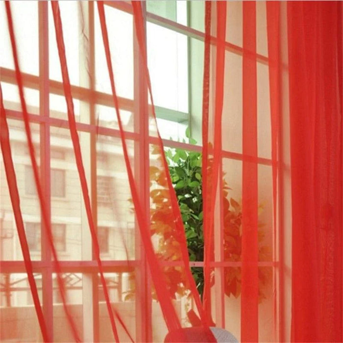 Rideaux rouges transparents laissant filtrer la lumière naturelle à travers une fenêtre, ajoutant une touche de couleur vive et élégante à la décoration intérieure. Une plante verte visible en arrière-plan crée un contraste esthétique et harmonieux. Parfaits pour embellir le salon ou la chambre tout en préservant l'intimité.