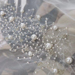 Voile de mariée délicatement orné de perles blanches, idéal pour une cérémonie élégante. Accessoire de mariage avec détails raffinés pour sublimer votre tenue nuptiale. Design romantique et sophistiqué, parfait pour une allure chic et inoubliable lors de votre grand jour.