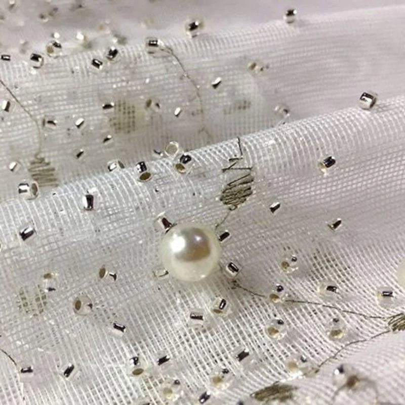 Tissu élégant avec motif perlé et détails scintillants, idéal pour les créations de mode sophistiquées et les décorations raffinées. Parfait pour ajouter une touche de glamour à vos projets couture et événements spéciaux.