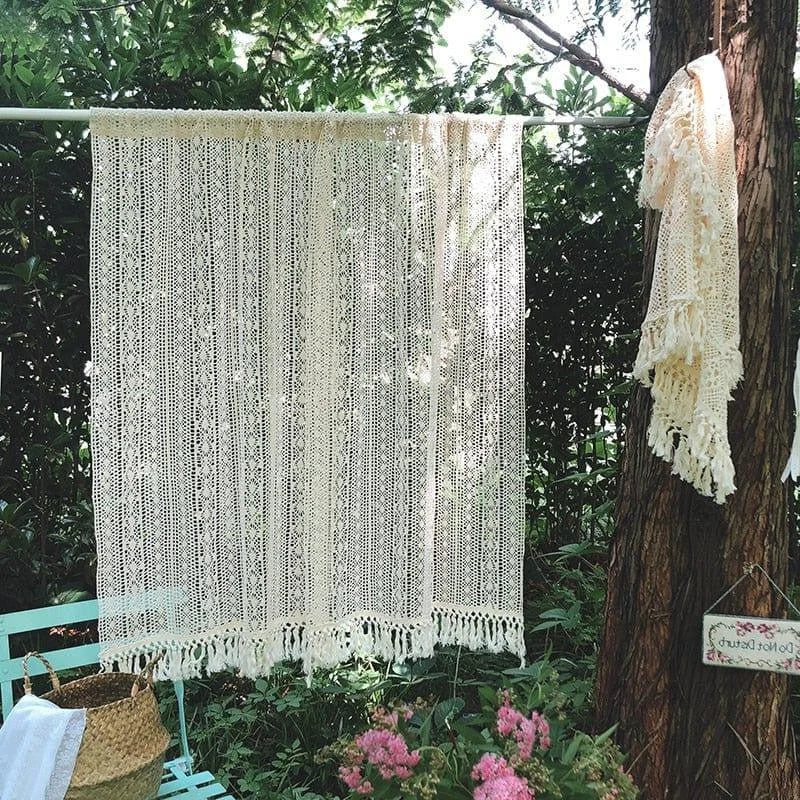 Rideau décoratif crochet beige suspendu dans un jardin verdoyant, idéal pour apporter une touche bohème à votre intérieur. Style artisanal avec franges, parfait pour créer une ambiance cosy et élégante. Parfait pour les salons, chambres ou espaces extérieurs couverts. Accessoire tendance pour personnaliser vos espaces avec charme et authenticité.