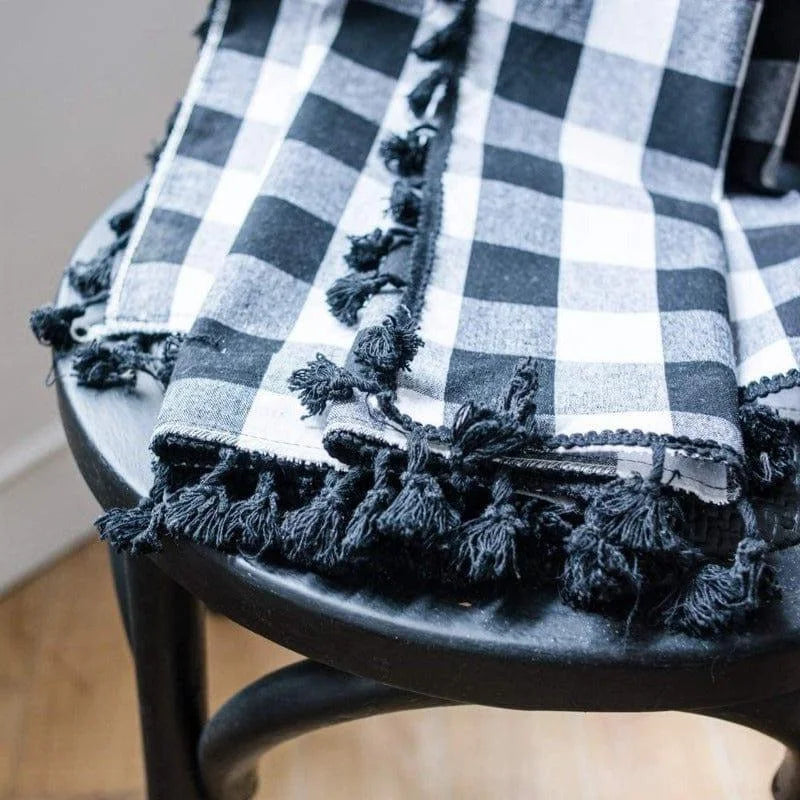 Serviette élégante à carreaux noirs et blancs avec franges, posée sur une chaise en bois noire. Parfaite pour ajouter une touche sophistiquée à votre décoration intérieure. Ideal pour les dîners ou les événements spéciaux.