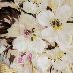 Image d'un tissu floral élégant avec des motifs de grandes fleurs blanches et des touches de jaune et de rose, idéal pour la décoration intérieure ou la confection de vêtements, ajoutant une touche printanière et raffinée à tout projet créatif.