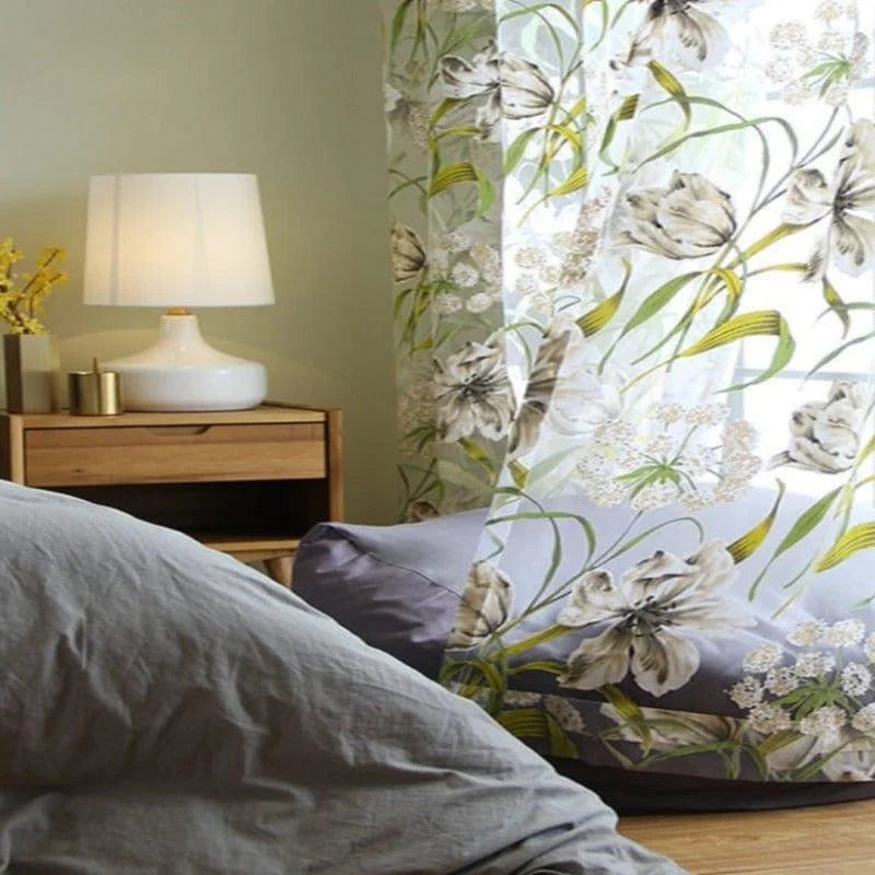 Rideau floral élégant dans une chambre moderne, ajoutant une touche de nature et de fraîcheur à l'espace. Le motif floral vibrant illumine la pièce, complété par une lampe de chevet design sur une table en bois, créant une ambiance chaleureuse et accueillante. Idéal pour une décoration intérieure harmonieuse et apaisante.