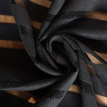 Image gros-plan d'un tissu noir à rayures transparentes, idéal pour la confection de vêtements élégants et modernes. Ce textile est parfait pour créer des effets de superposition raffinés et ajoutera une touche de sophistication à vos créations vestimentaires.