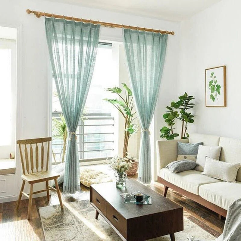Salon moderne et lumineux avec rideaux turquoise, canapé confortable, table basse en bois et décoration végétale. Ambiance accueillante et élégante pour un intérieur chaleureux et stylé.